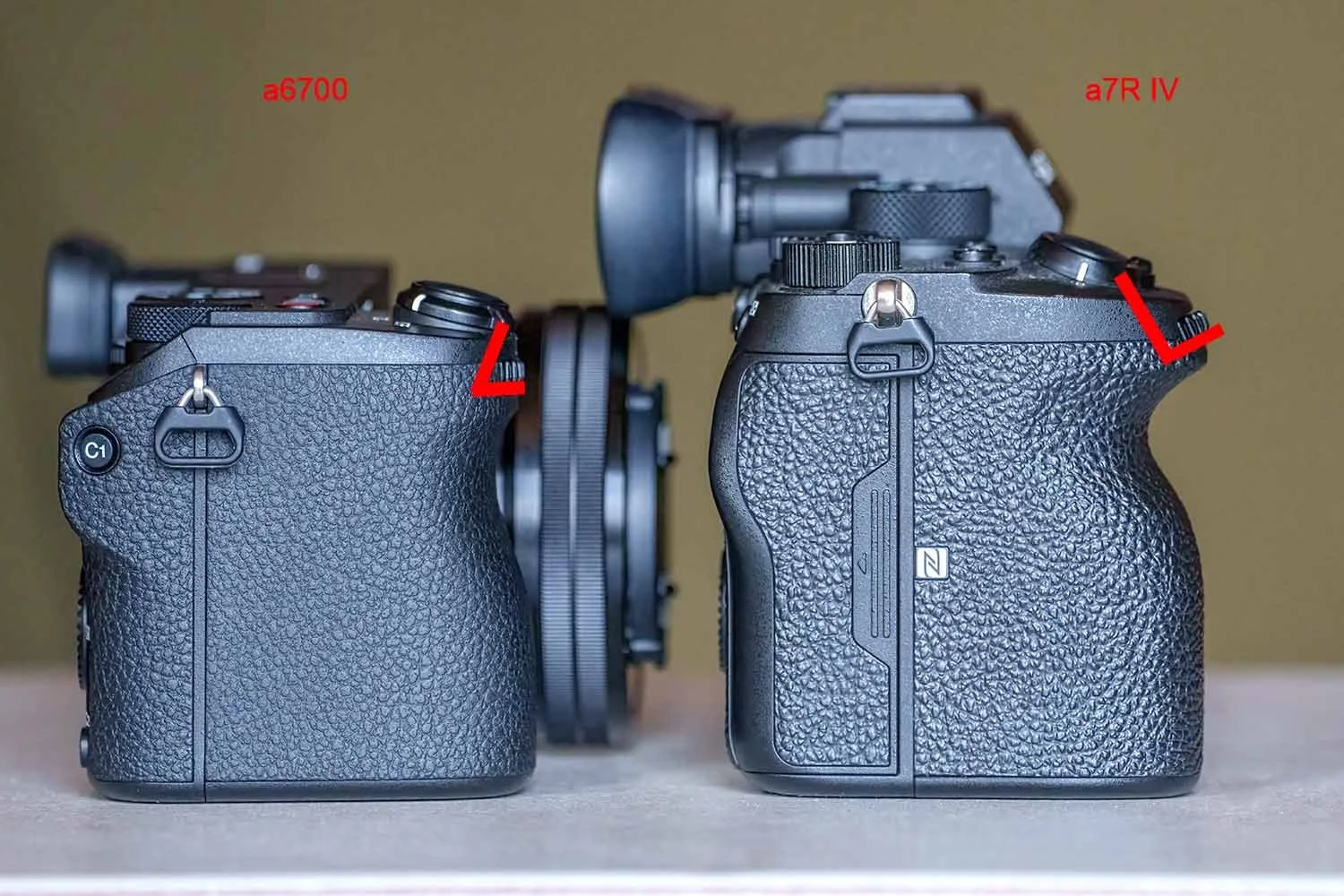 Sony a6700 und a7R IV seitlich nebeneinander, rote Markierungen vergleichen die Handgriffe beider Kameras.