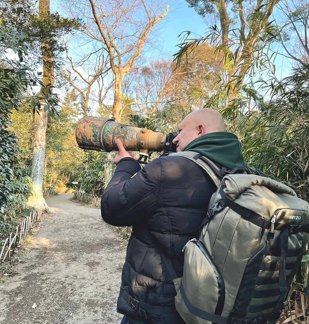 Markus fotografiert mit Teleobjektiv auf einem Weg zwischen Bambus und Bäumen.